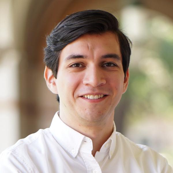 Headshot of Enrique Quezada with a natural background.